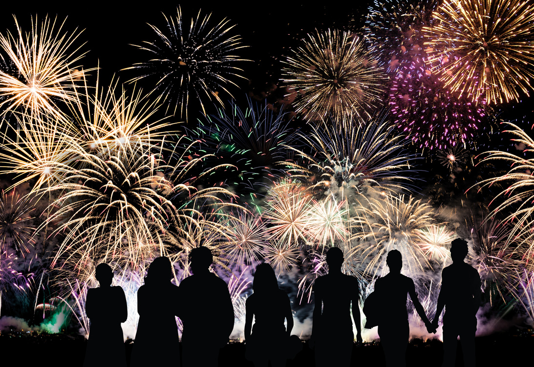 Group of people watch colorful holiday fireworks